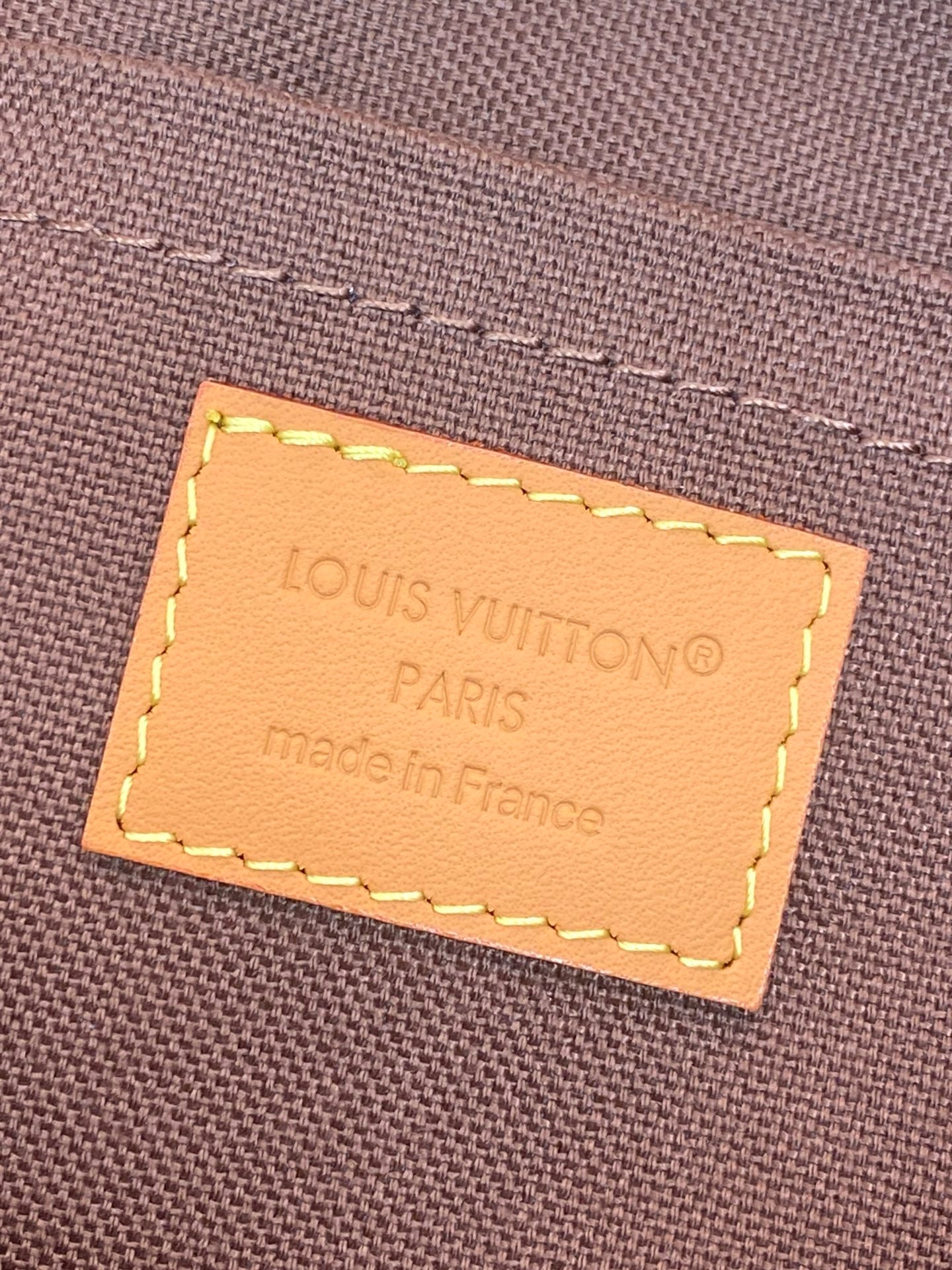 Leather brand label on small monogram pouch bag: Louis Vuitton Paris, made in France