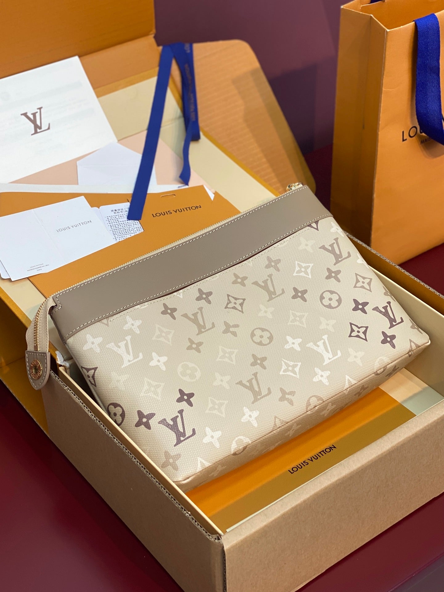 Small monogram pouch bag, beige canvas with repeating pattern and gold zipper top