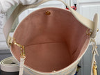Louis Vuitton bag interior view with brown lining and gold hardware rings on light beige
