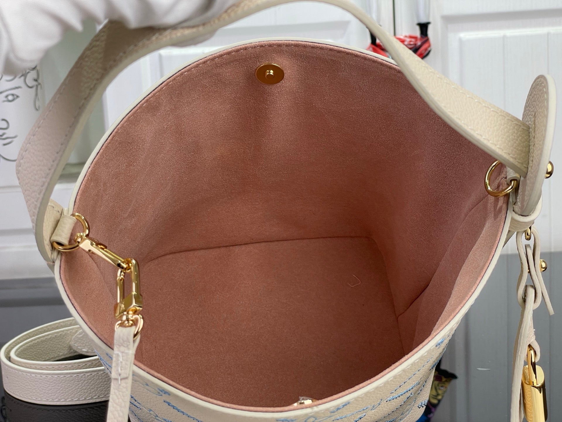 Louis Vuitton bag interior view with brown lining and gold hardware rings on light beige