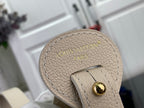 Louis Vuitton bag base with embossed "Louis Vuitton" and gold button on light beige leather