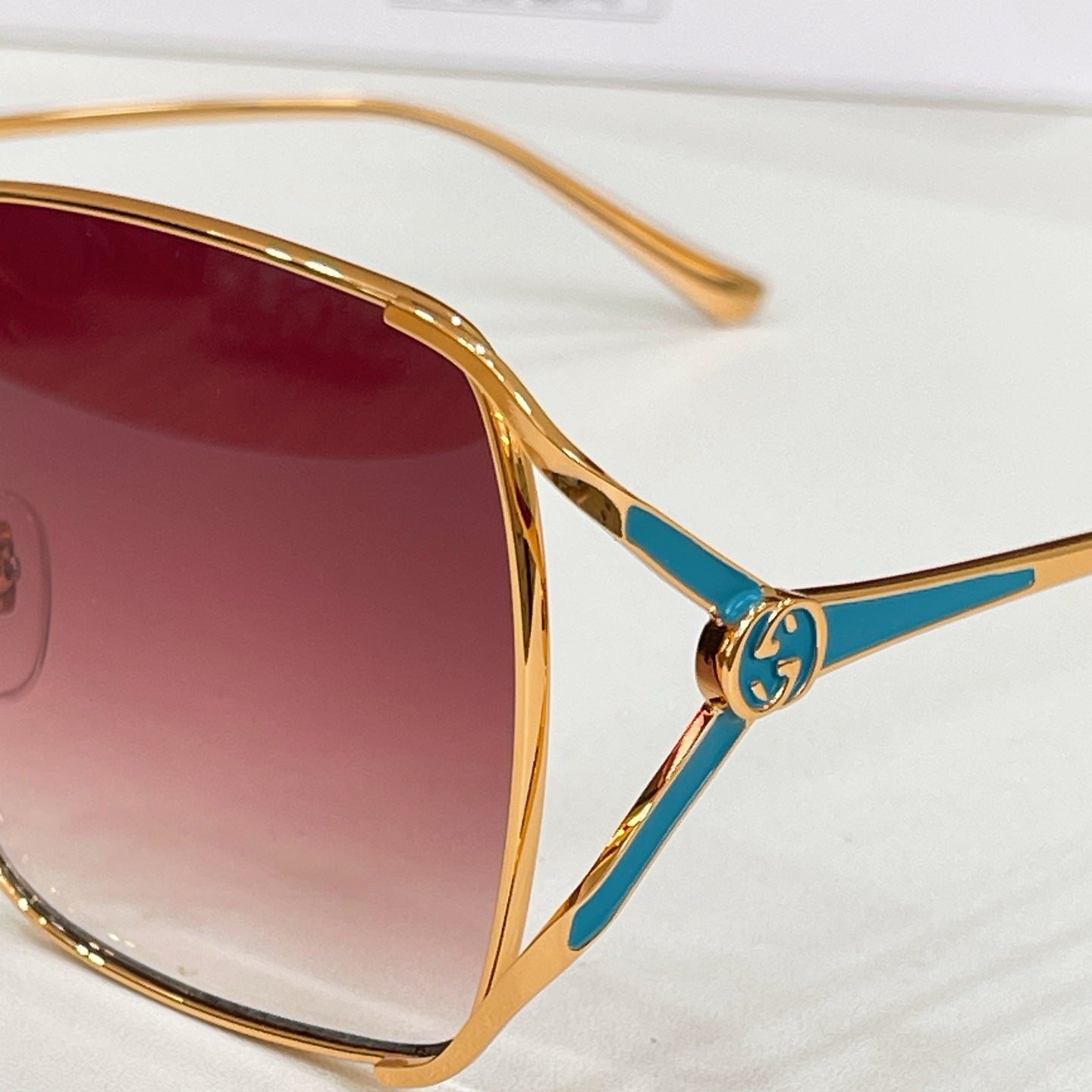 Gucci sunglasses temple detail with gold frame and blue enamel logo
