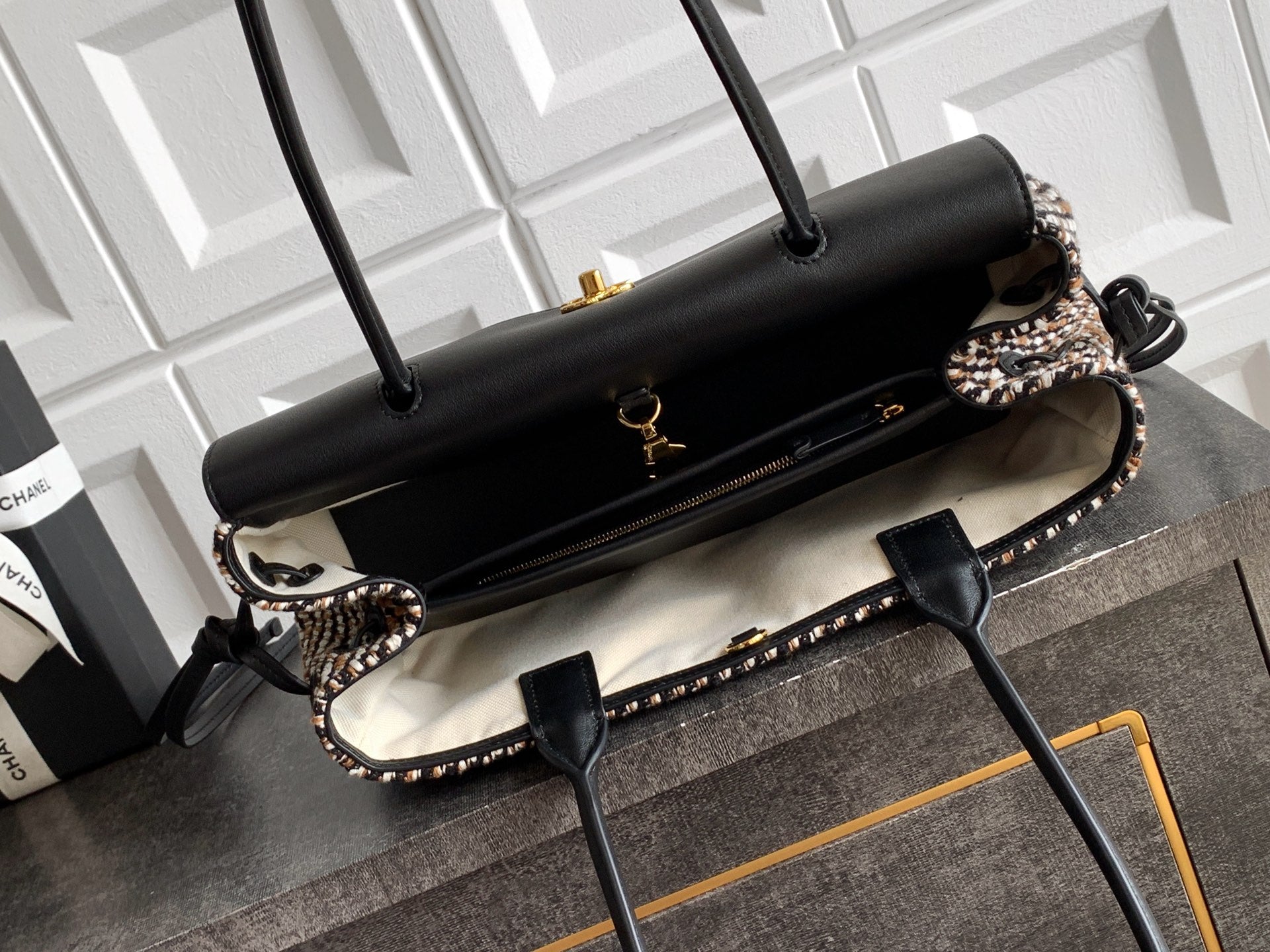 Chanel handbag with black leather flap and houndstooth side panels, gold-tone feet.
