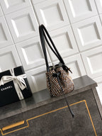 Chanel handbag with tall black leather handles and houndstooth woven body, gold accents.