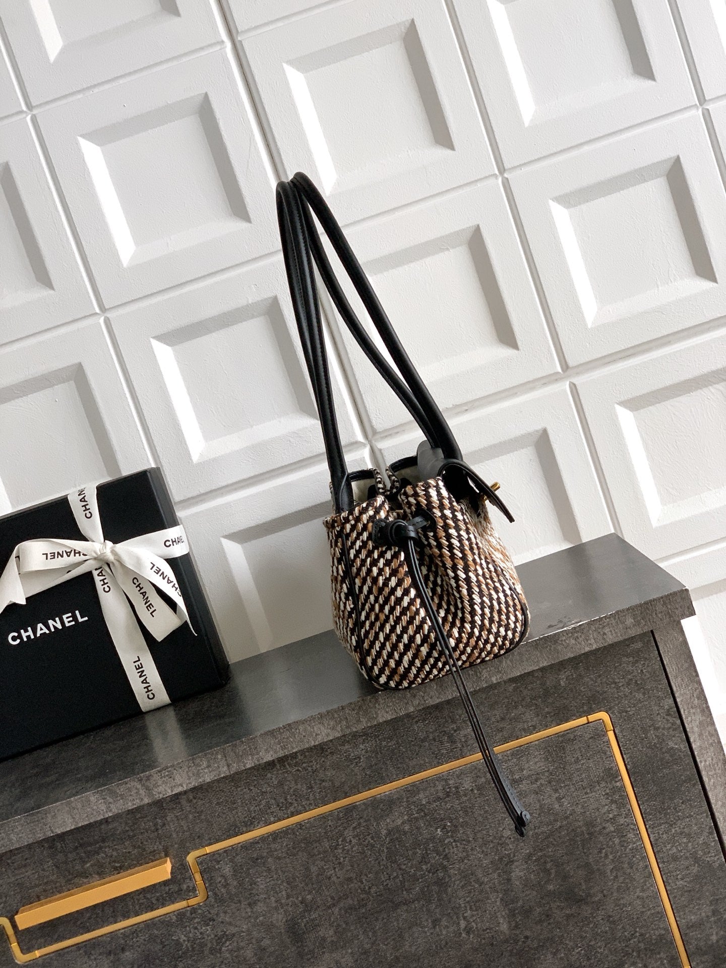 Chanel handbag with tall black leather handles and houndstooth woven body, gold accents.