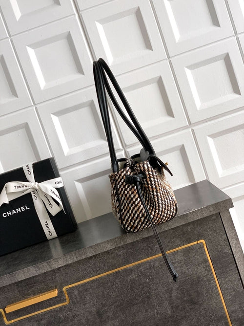 Chanel handbag with tall black leather handles and houndstooth woven body, gold accents.