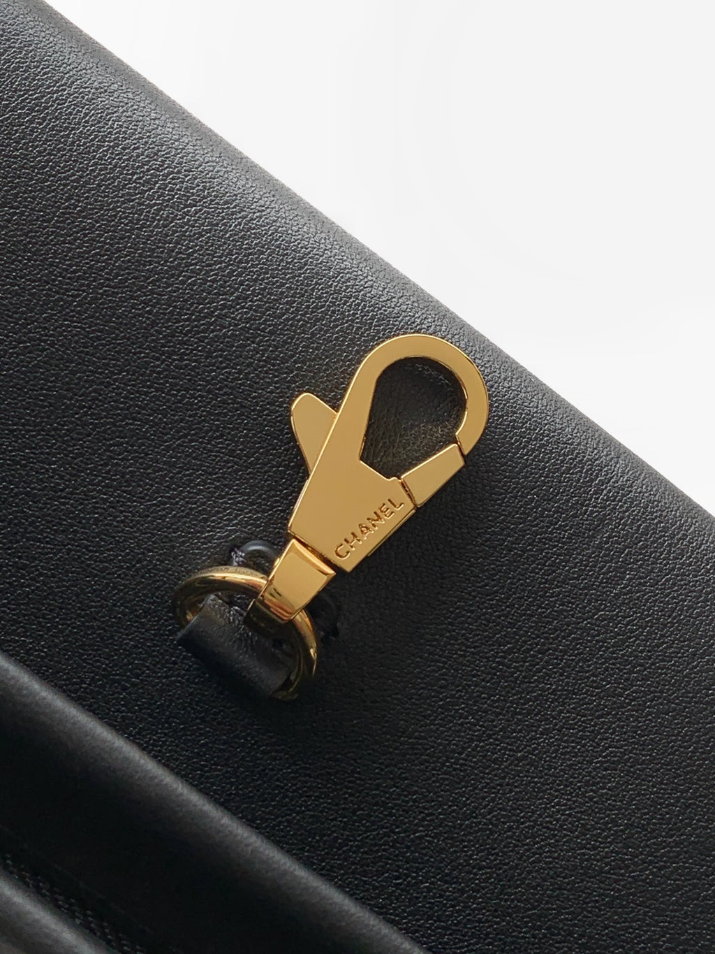 Chanel bag close-up: gold clasp hardware on black leather with stitched seam detail.