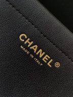 Chanel bag label detail: gold CHANEL text on black leather with stitching.