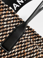 Black leather trim on multicolor tweed handbag with visible stitching and edge panel