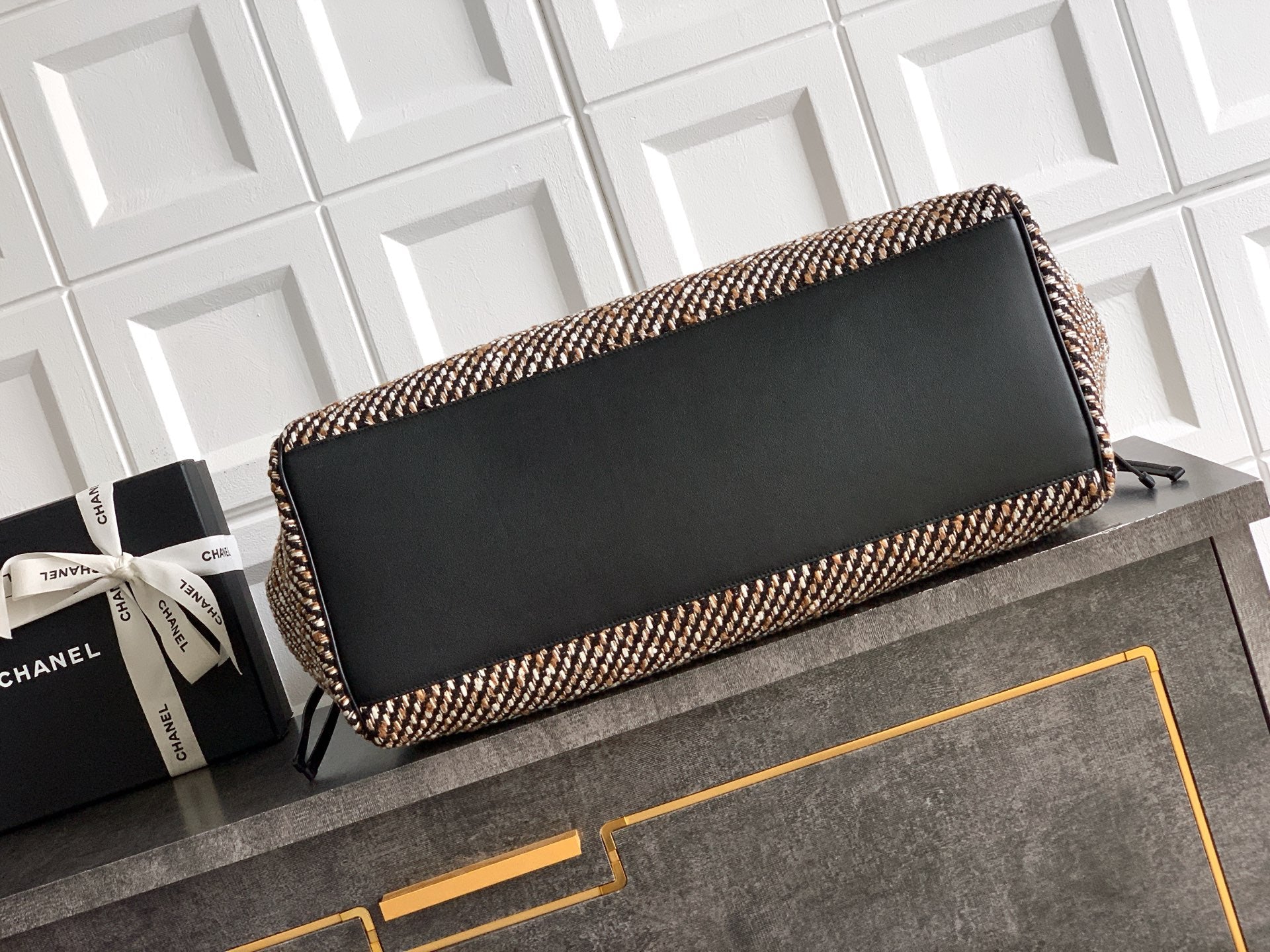 Black flap tweed clutch-style handbag with gold-trim edge and fabric tassel ends