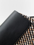 Black leather corner of tweed handbag with trim edge and stitched seam detail