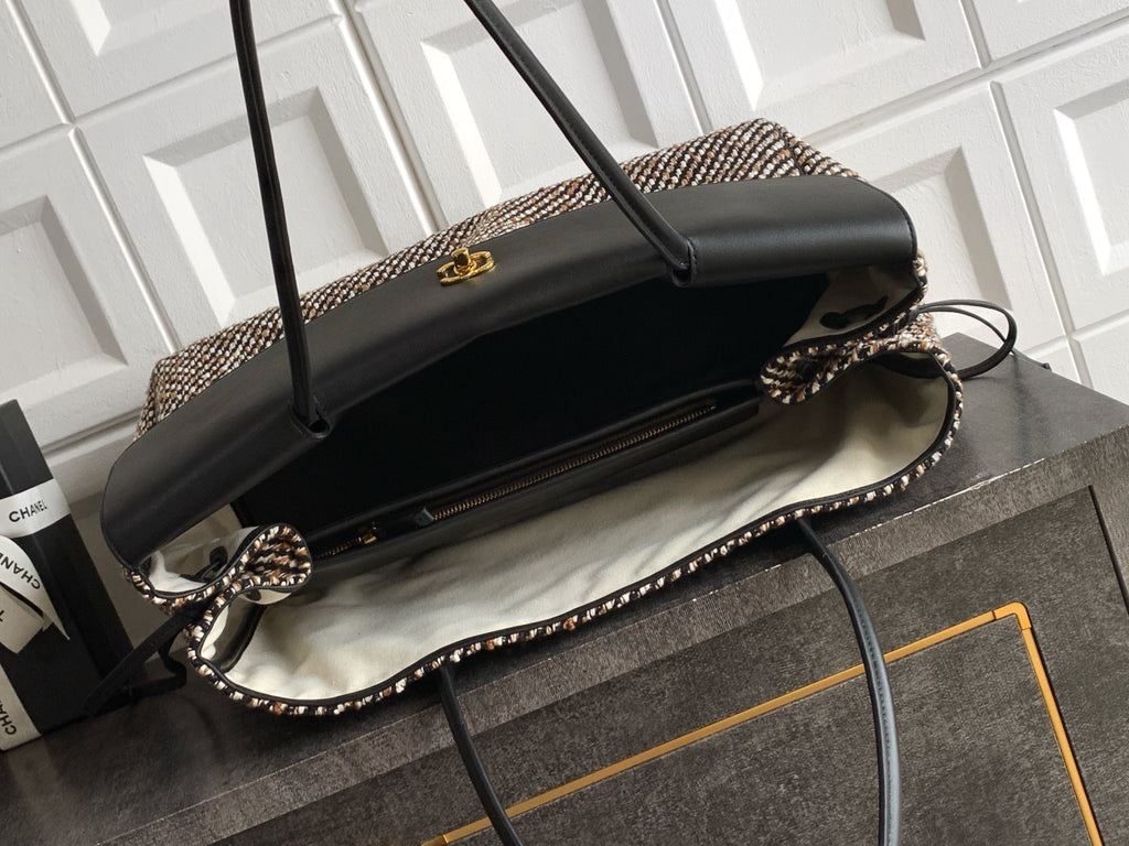 Open black-and-tweed handbag with black lining and gold-tone clasp on top