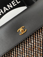 Chanel black leather flap with gold CC logo and stitched edge on tweed trim