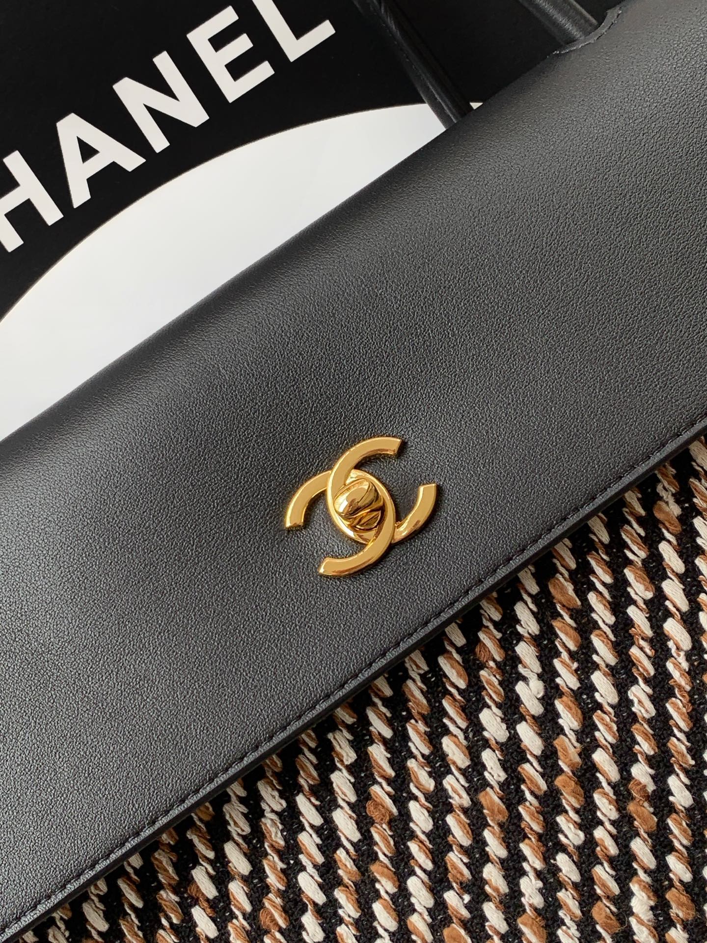 Chanel black leather flap with gold CC logo and stitched edge on tweed trim