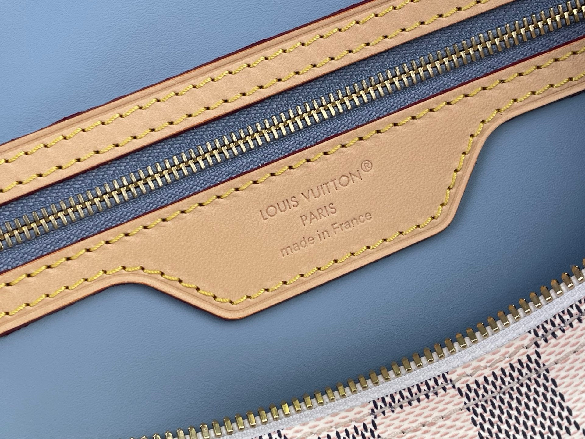 Louis Vuitton Paris label on light blue leather bag with gold zipper and stitched trim