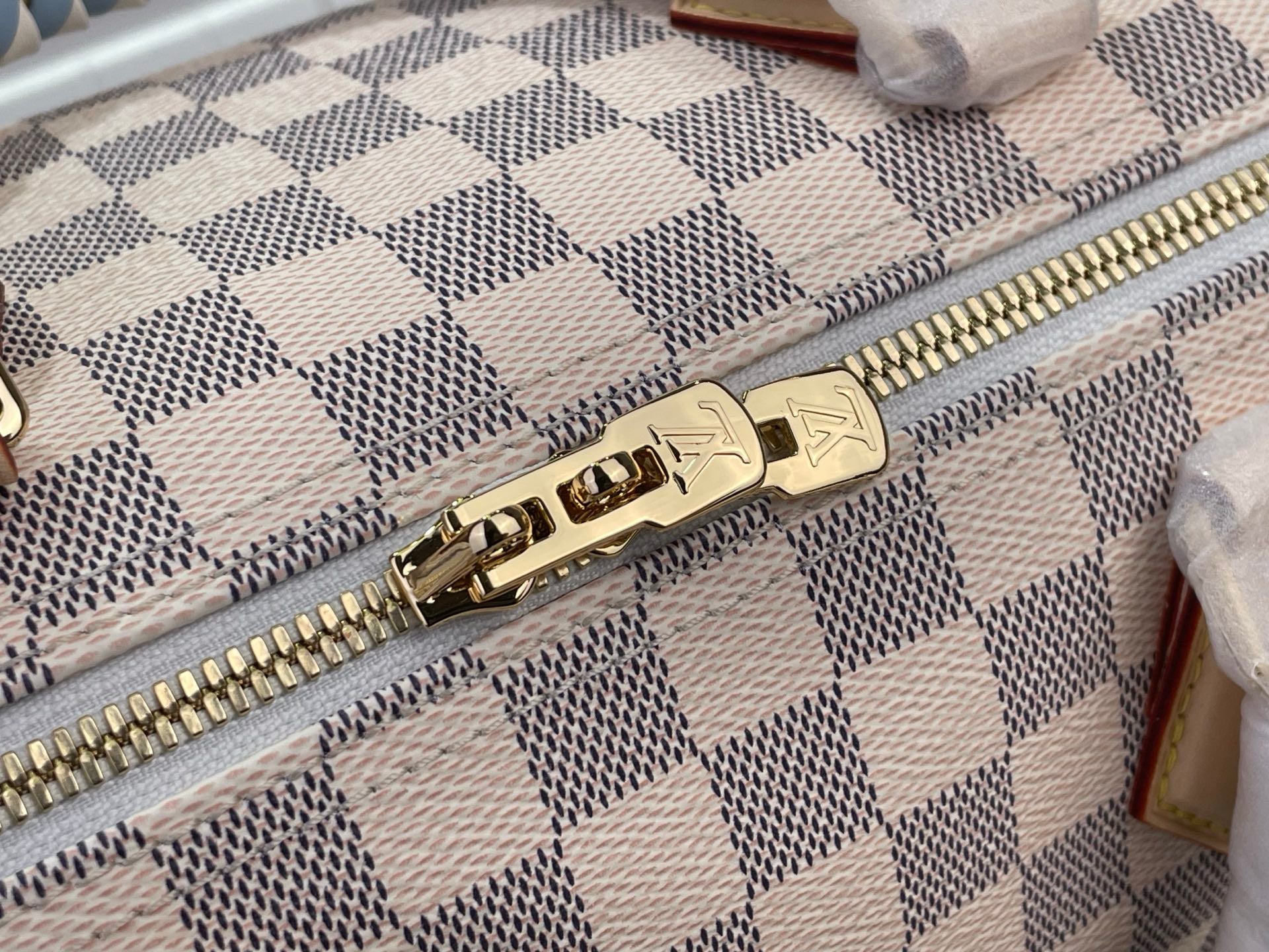 Louis Vuitton Damier handbag zipper close-up with gold-tone hardware