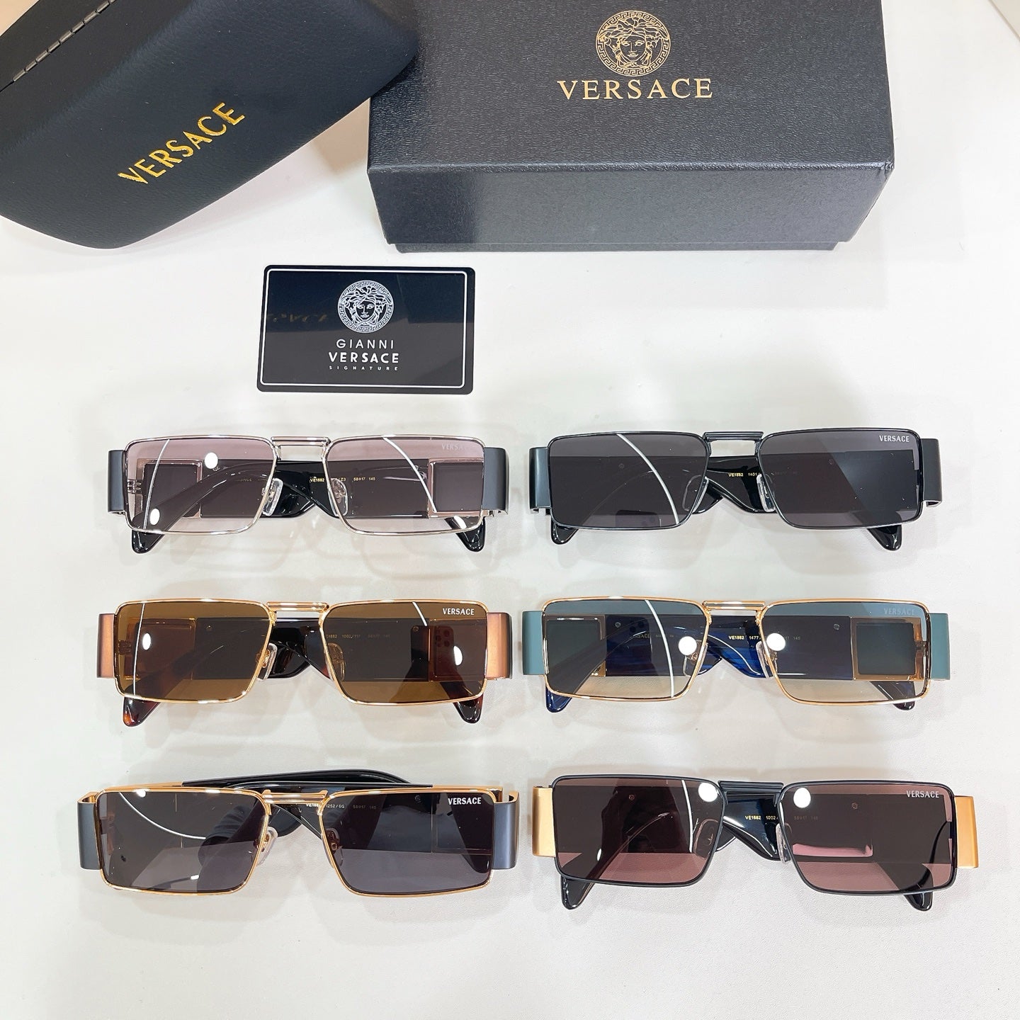 Assorted sunglasses with black and gold frames beside a case and label card.