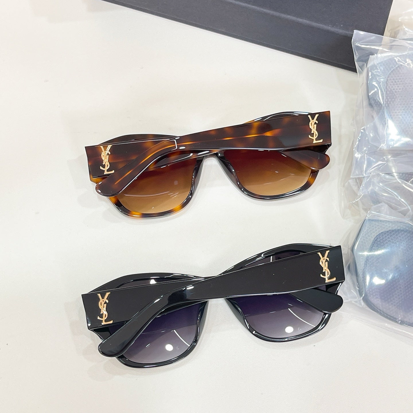 Brown and black cat-eye sunglasses with gold logo arms and tinted lenses.