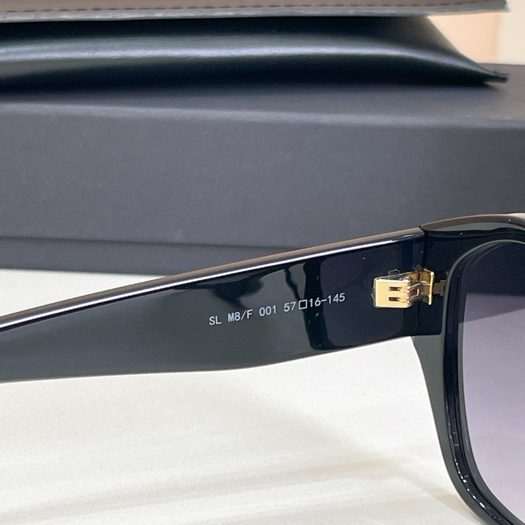 Black sunglasses temple close-up with engraved markings and gold hinge detail.