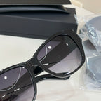 Black cat-eye sunglasses close-up with dark tinted lenses and glossy frame.