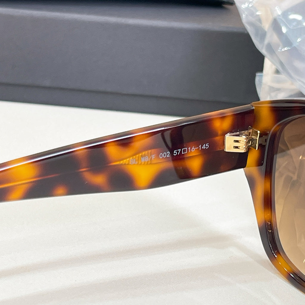 Tortoiseshell sunglasses temple close-up with gold metal logo