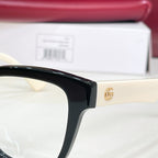 Gucci acetate glasses close-up: black frame with gold interlocking logo, clear lens