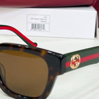 Gucci sunglasses close-up with brown lenses, dark frames, red-and-green temple and GG emblem