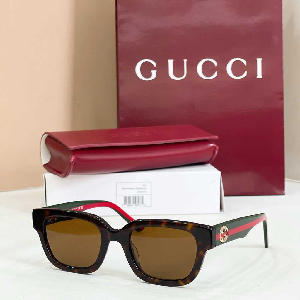 Gucci sunglasses with dark lenses and dark tortoiseshell-look frames, striped red-green temples