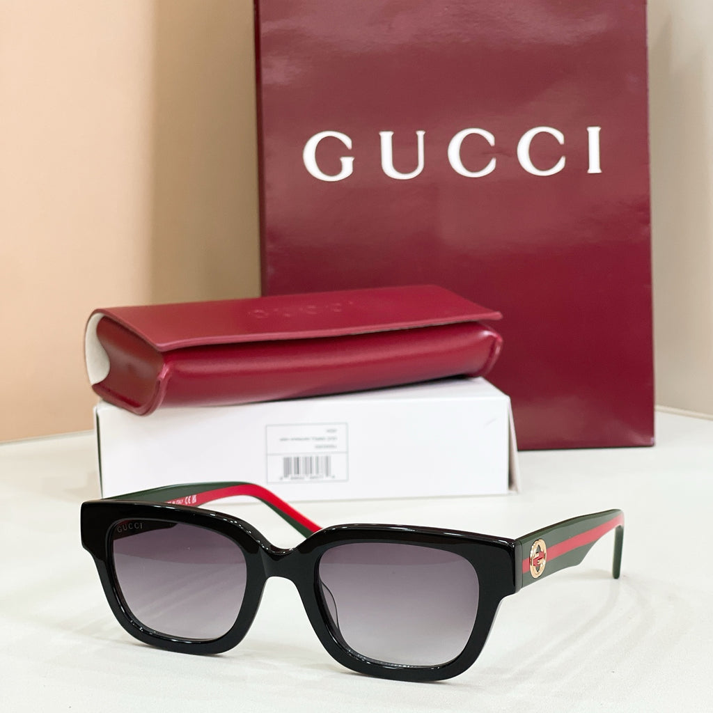 Gucci sunglasses with black frames and tinted lenses, red-and-green striped temple arms