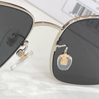 Gucci sunglasses close-up of gold bridge with dark lenses and rhinestone detail