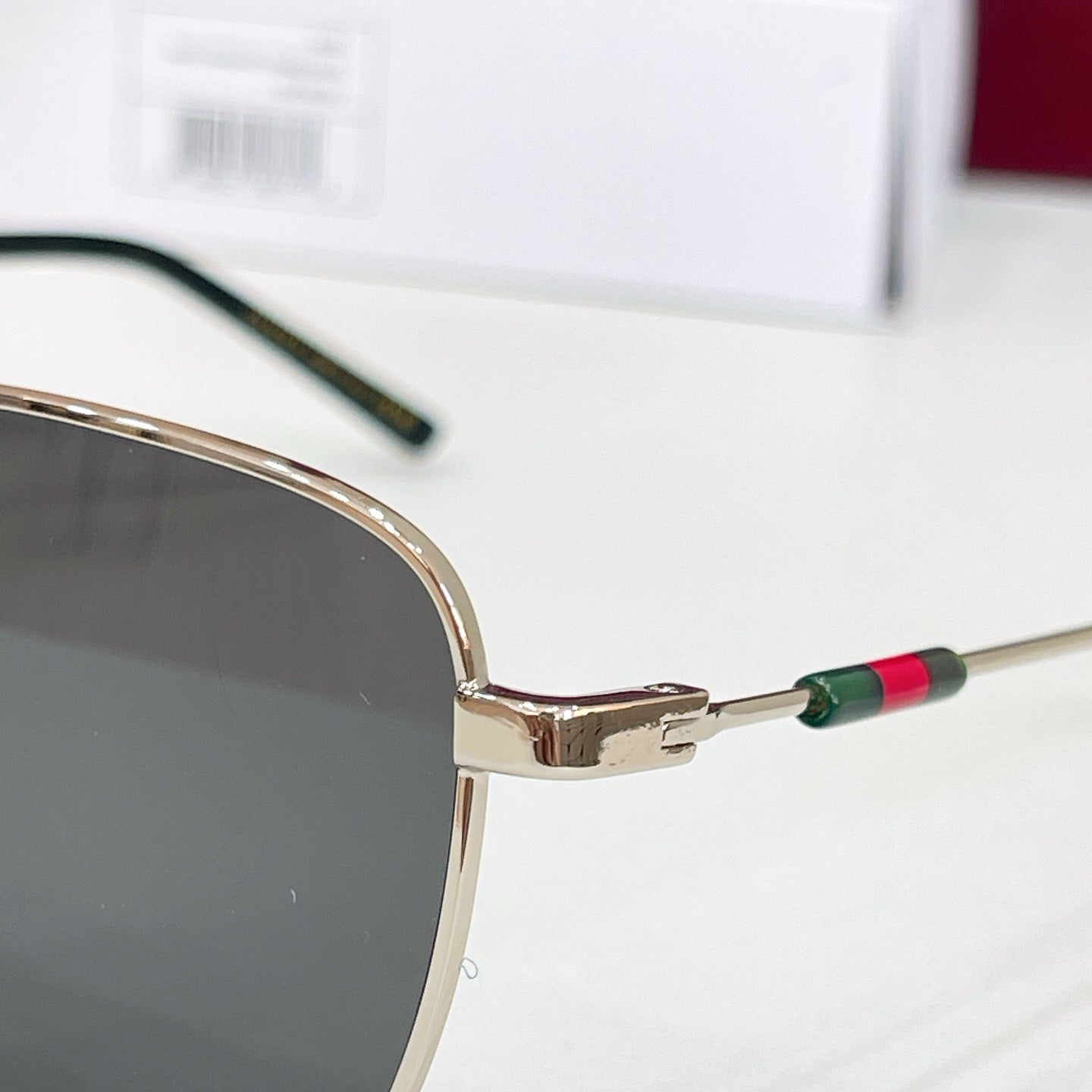 Gucci sunglasses close-up of gold temple with multicolor stripe and dark lens