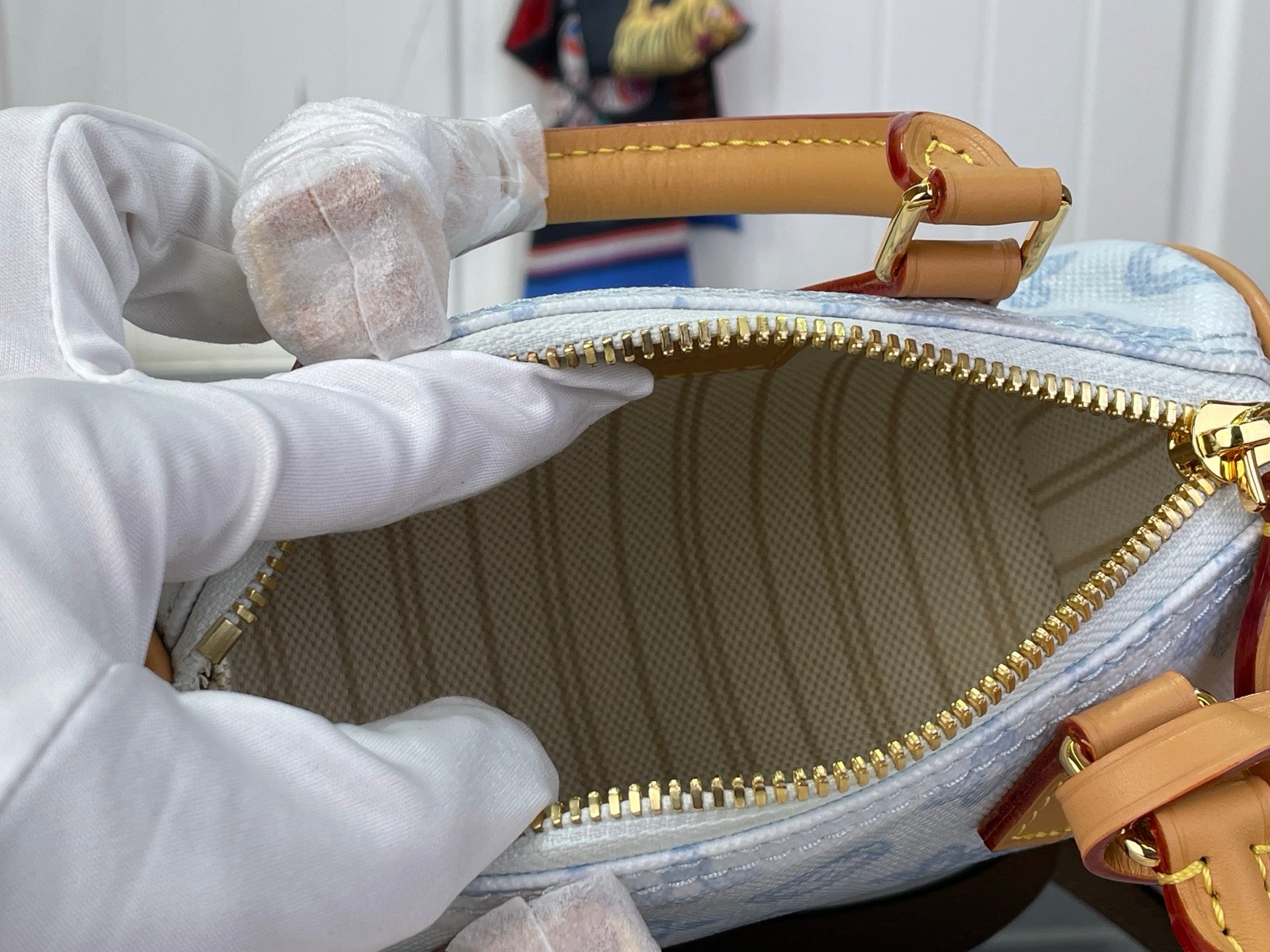 Louis Vuitton bag interior with gold zipper, tan trim, and light blue monogram lining