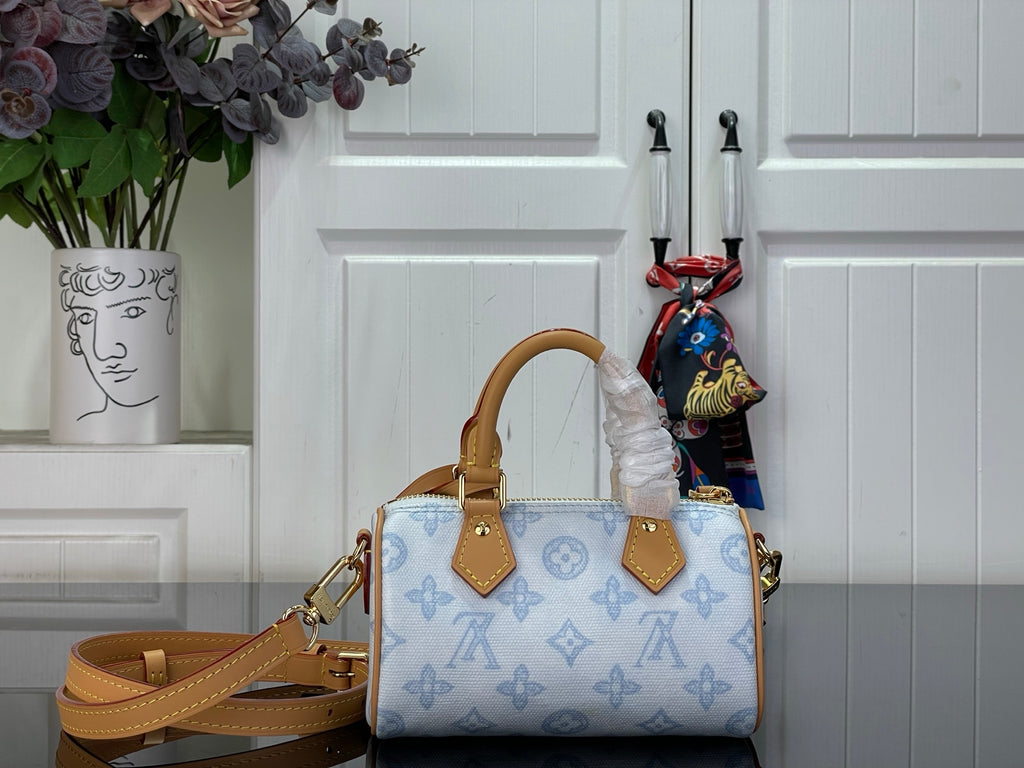 Louis Vuitton handbag with light blue monogram, tan shoulder strap, and top handles