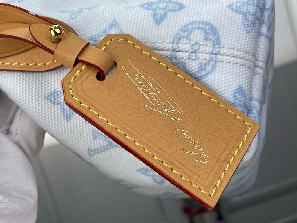 Tan leather nameplate and brown strap on light blue monogram canvas bag