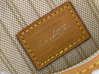 Tan leather brand patch with yellow stitching on light blue monogram canvas bag
