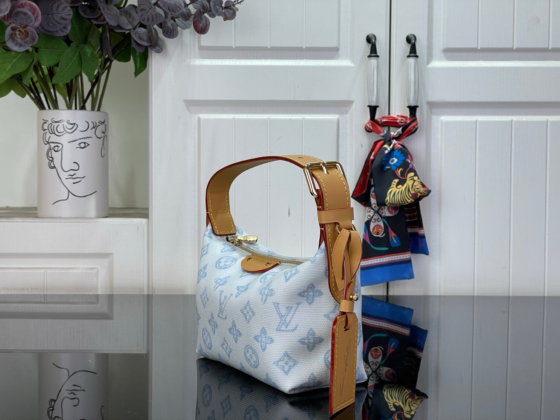 Light blue monogram canvas bag with tan leather top handle and curved silhouette