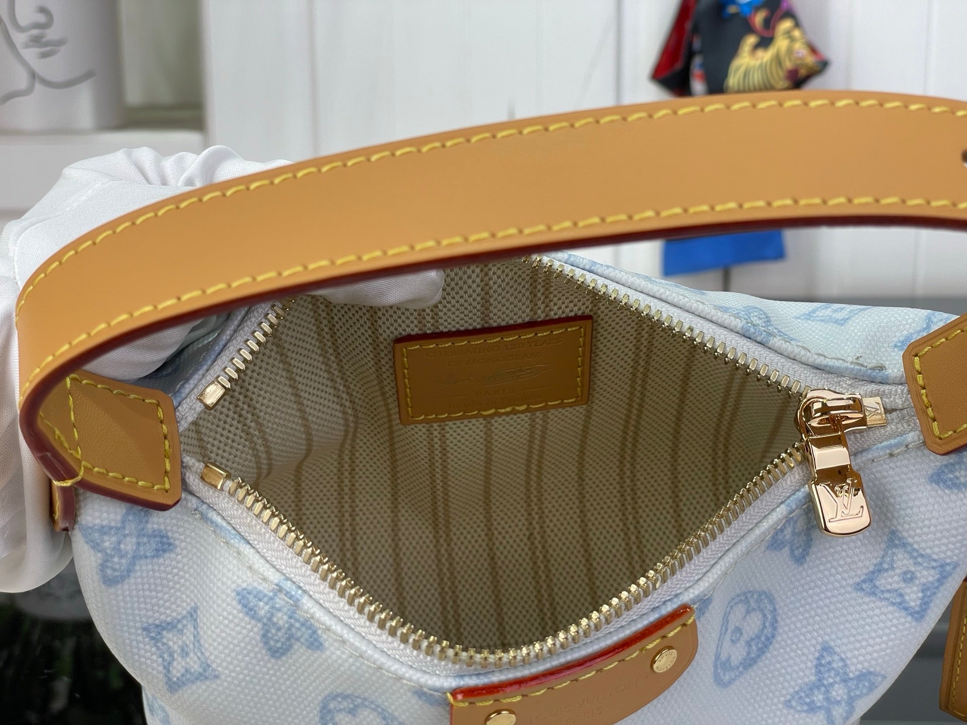 Opened light blue monogram bag interior with tan lining and zip pocket