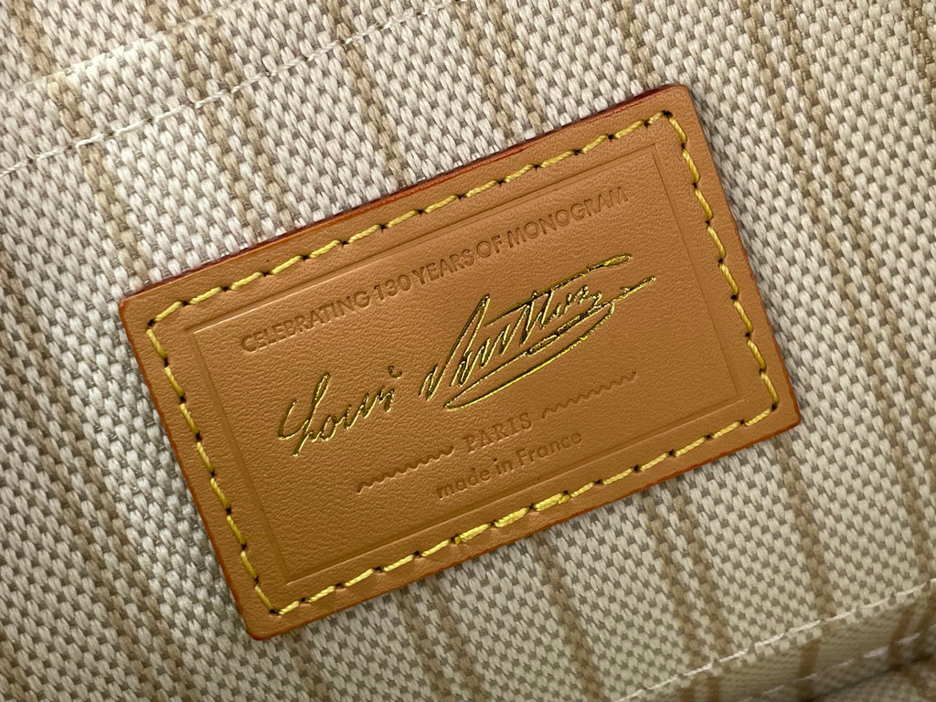 Tan brand label with embossed text and gold stitching on beige canvas lining.