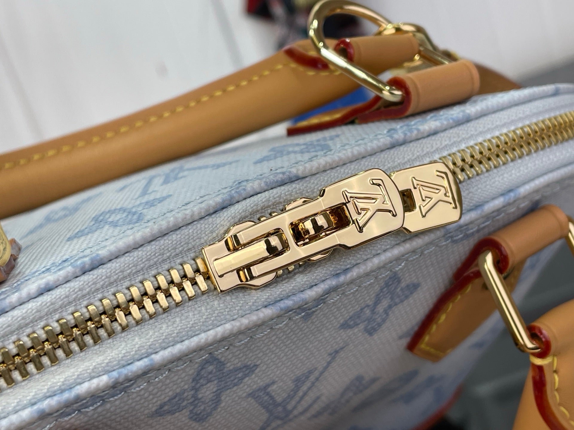Blue monogram bag zipper with gold Louis Vuitton hardware and pull tab detail.