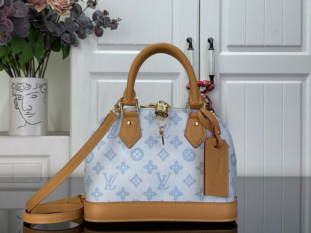 Louis Vuitton monogram handbag with blue canvas and tan leather handles, top zipper.