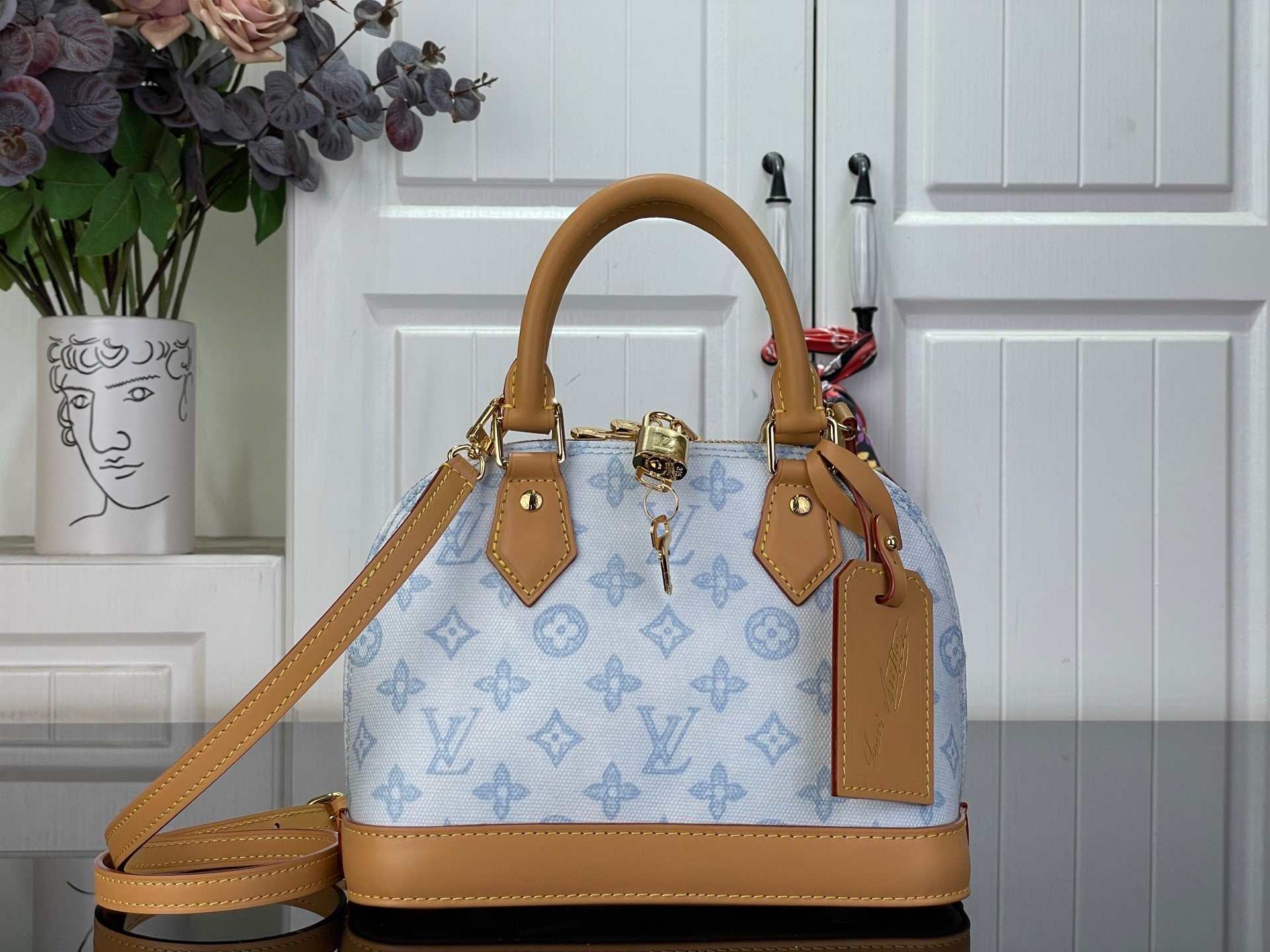 Louis Vuitton monogram handbag with blue canvas and tan leather handles, top zipper.