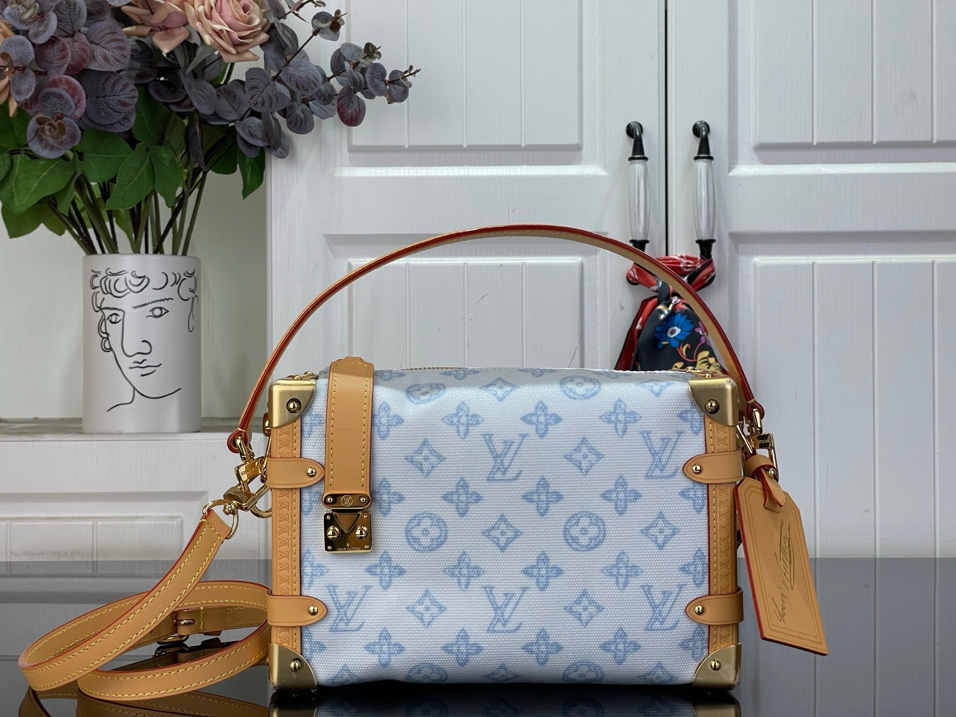 Blue monogram handbag with tan leather trim, gold hardware, and crossbody strap