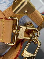 Blue monogram handbag close-up: gold clasp and key ring hardware with tan leather