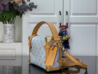 Blue monogram handbag side view with tan leather strap and gold hardware
