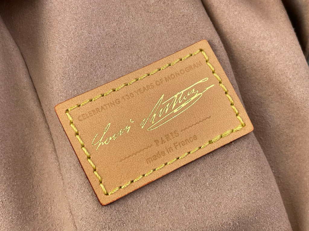 Leather Louis Vuitton bag label patch with green-stitched border and script logo