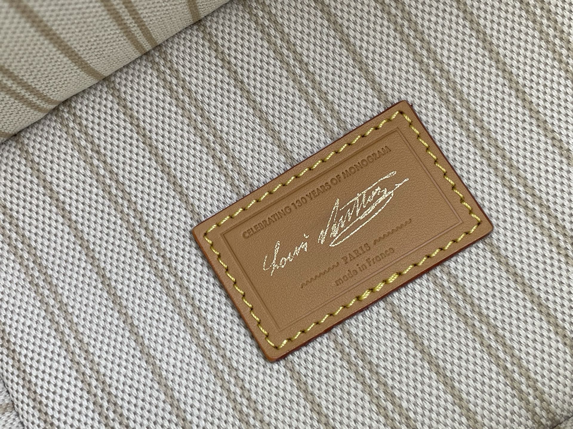 Louis Vuitton interior label on fabric lining with stitched tan leather frame