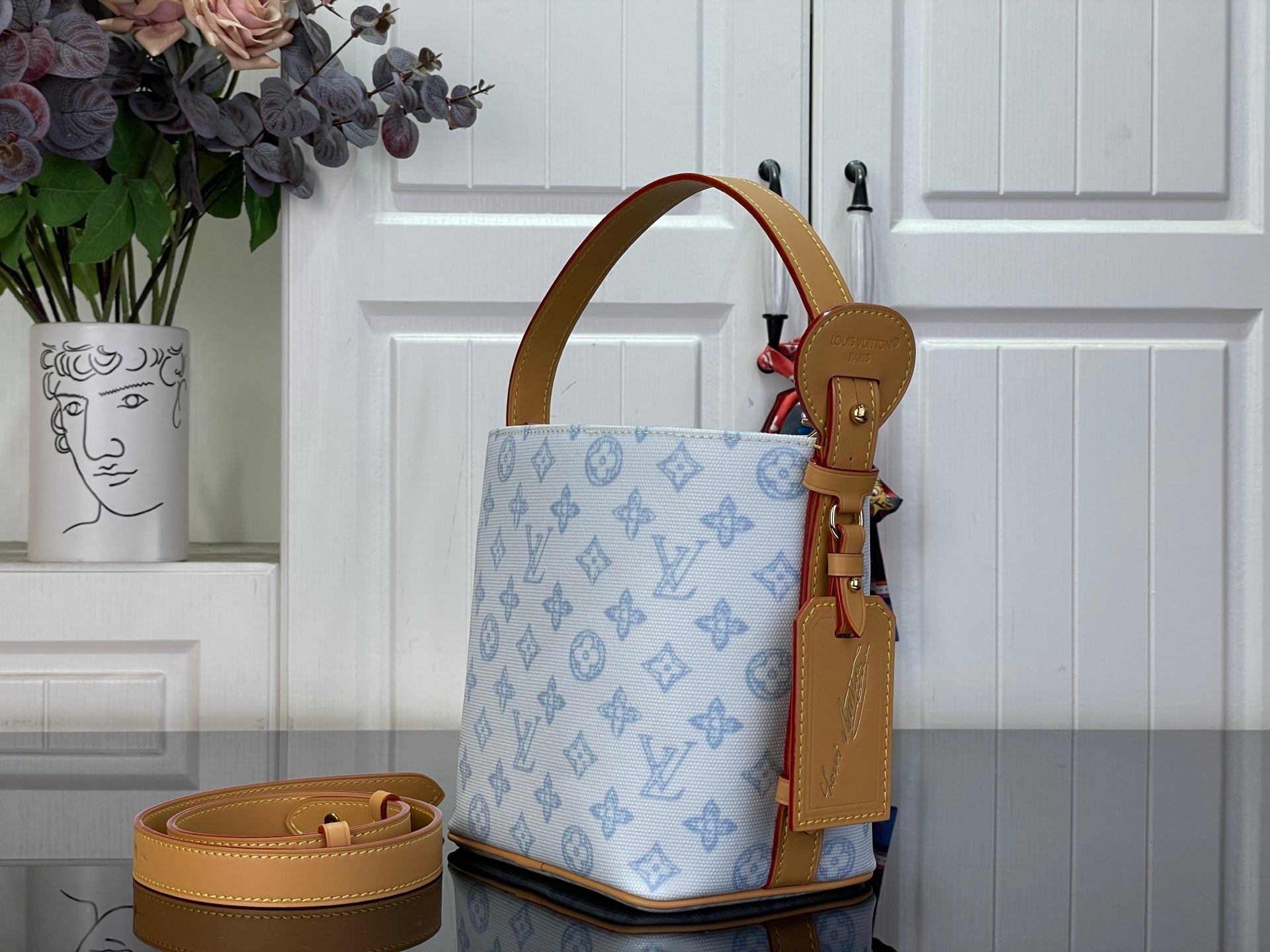 Louis Vuitton tote bag side view in light blue monogram canvas with tan leather strap details
