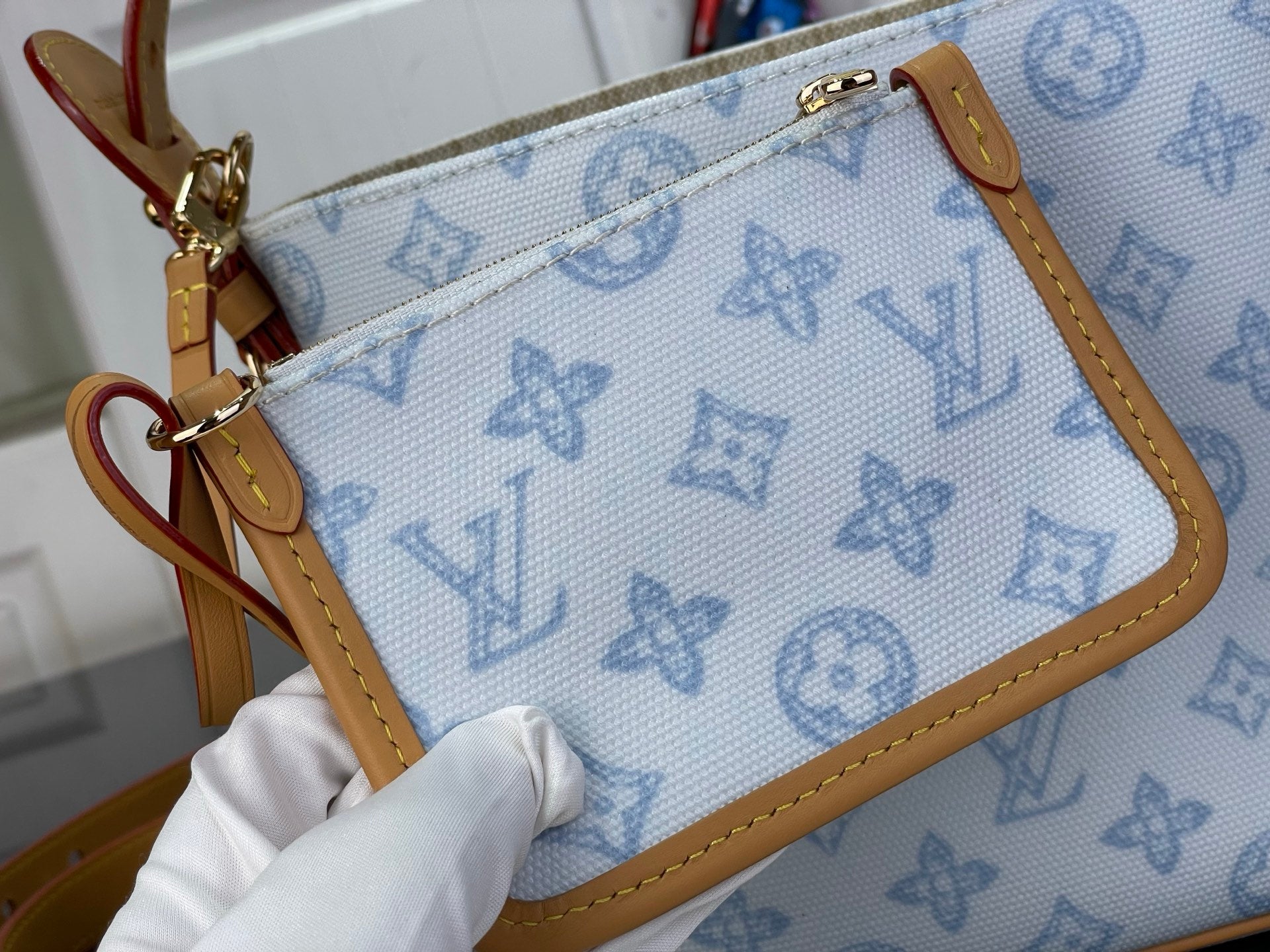 Louis Vuitton monogram wristlet with tan strap, gold clasp, and light blue patterned body
