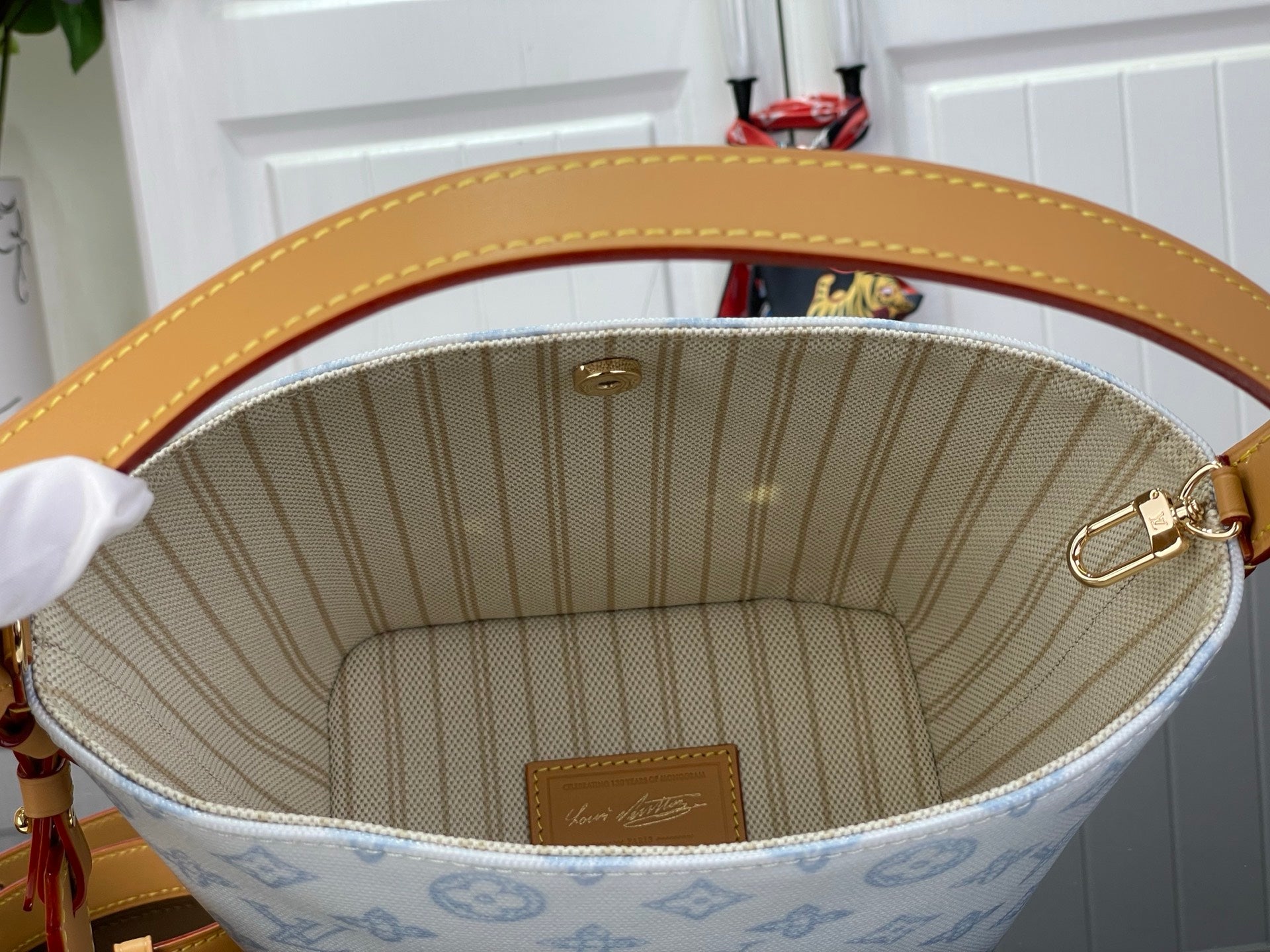 Louis Vuitton bag interior view with light blue monogram lining and tan leather top rim