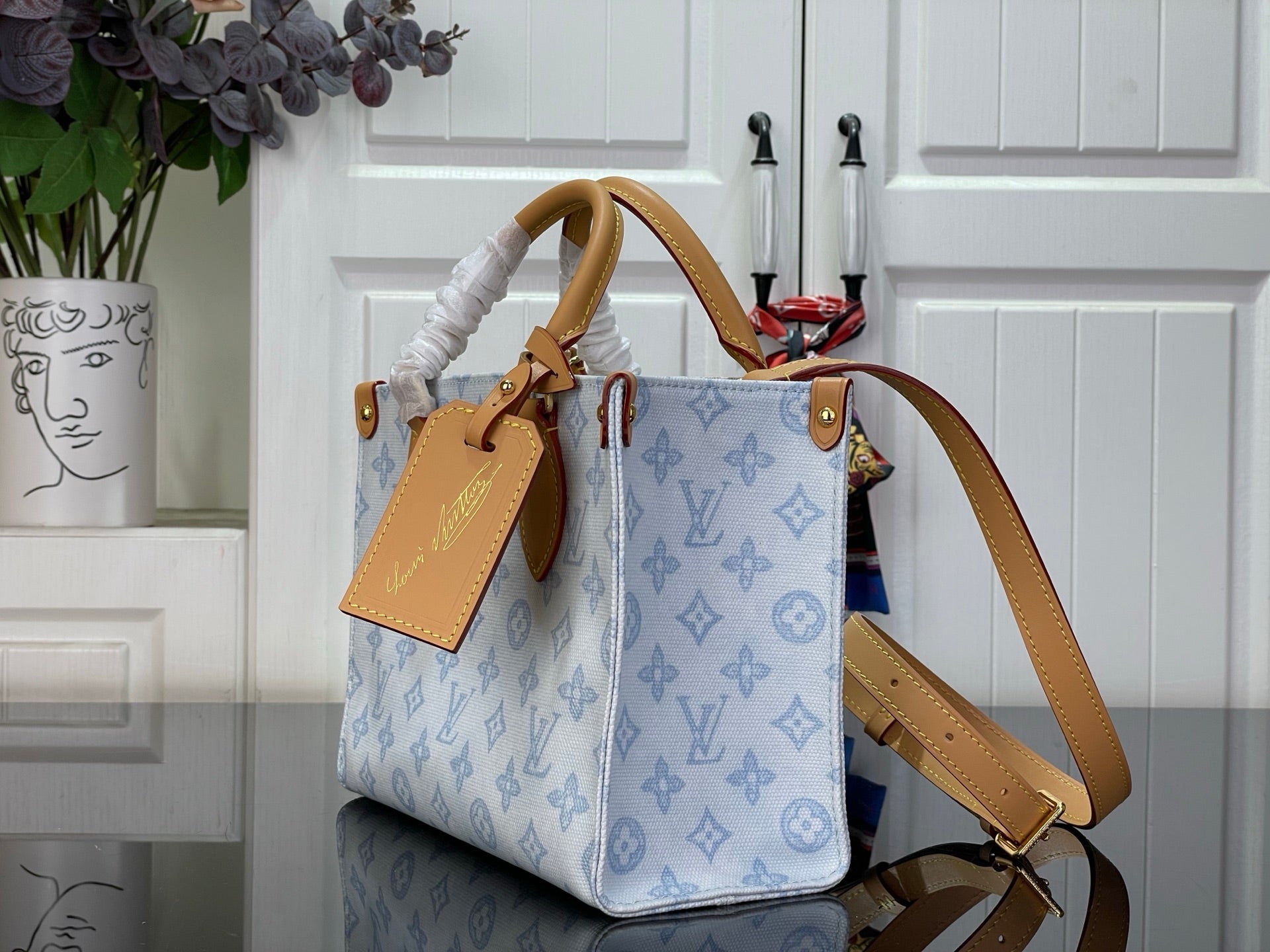 Louis Vuitton blue monogram top-handle bag with tan shoulder strap and charm